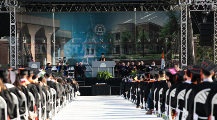 Mercer to confer honorary degrees to state Senator John F. Kennedy and Zelma Redding student speaks at a podium in front of graduates