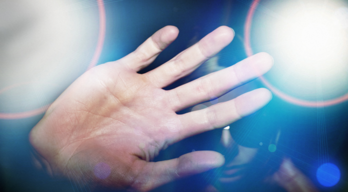 Professor’s research explores factors that could lead to celebrity stalking man holds hand out in front of face amid flashing lights