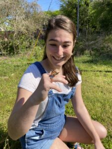 Genevieve Haskins looks at a butterfly on her finger