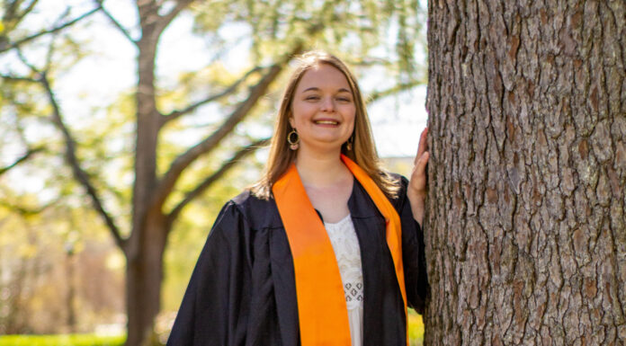 Graduate Spotlight: Gwenevere Wrye Gwenevere Wrye wears a black graduation gown and orange stoll