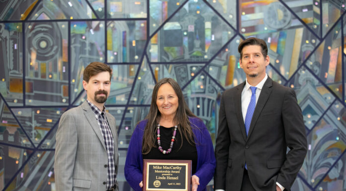 Biology professor awarded 2023 Mike MacCarthy Mentorship Award two men stand on either side of a woman holding an award plaque