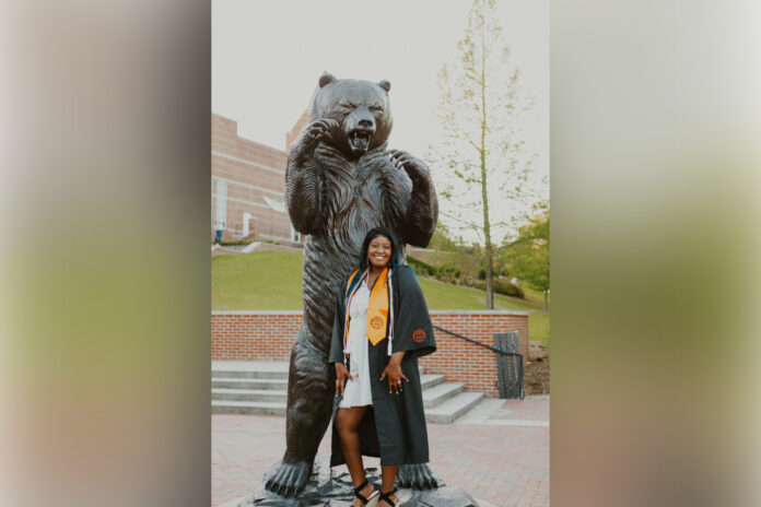 necole gonsahn stands in front of the bear statue