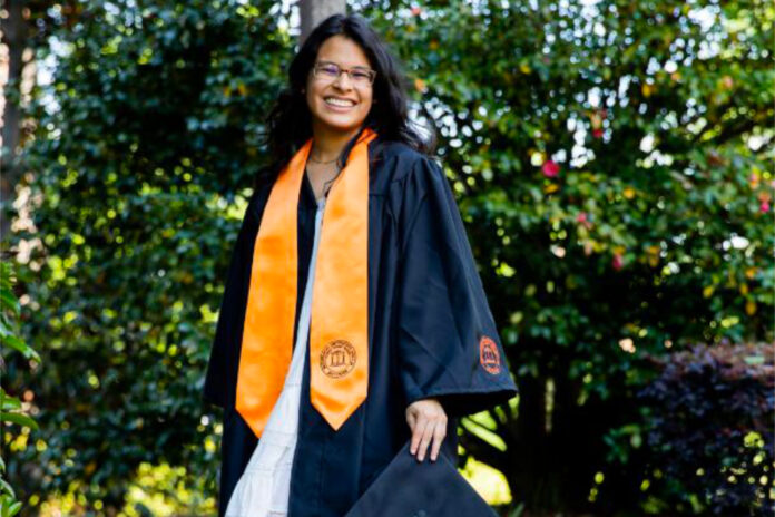 Sara Davila Severiano wears her graduation gown and orange stole