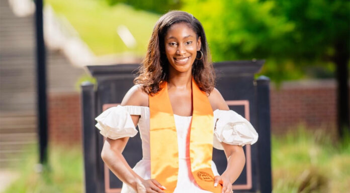 Graduate Spotlight: Emily Ogbodo Emily Ogbodo wears a white dress and orange stoll