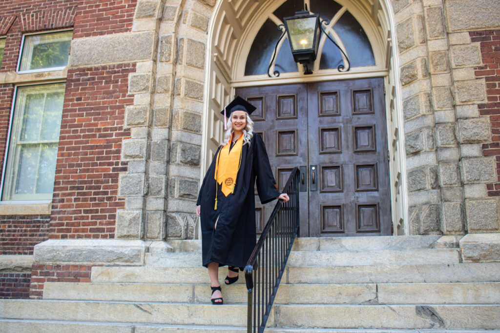 kristin ware stands on steps while wearing graduation gown