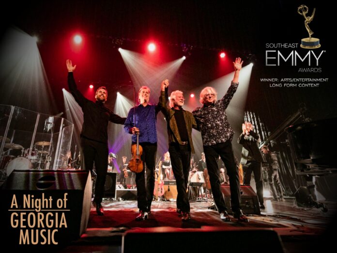 ward stare, robert mcduffie, chuck leavell, and mike mills hold hands and lift their arms on stage