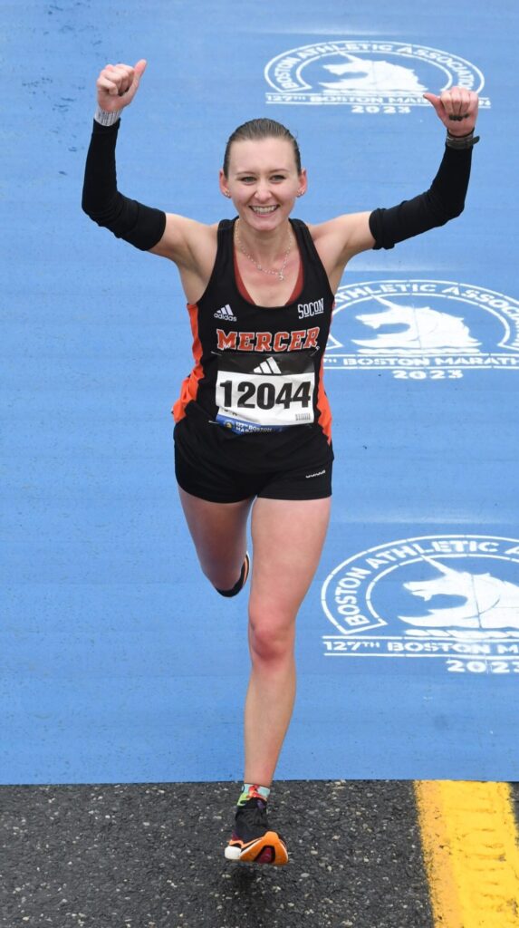 Marina Van Sickle gives two thumbs up while running the Boston Marathon. She's wearing her Mercer track uniform.