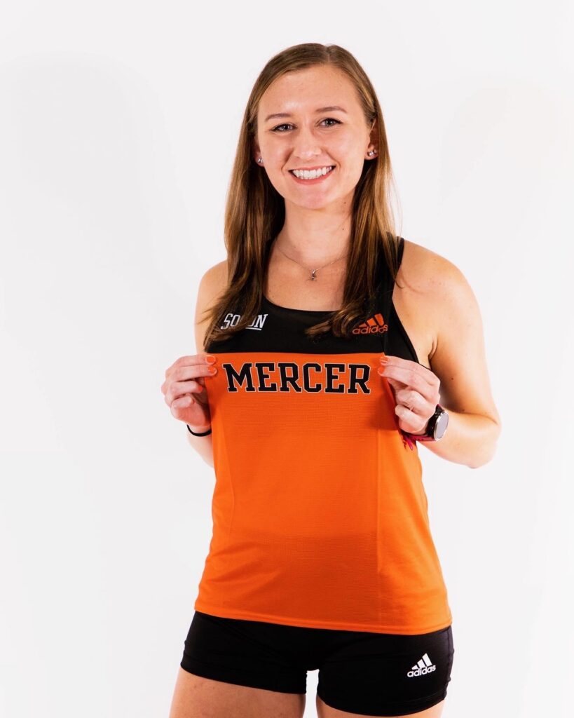 Marina Van Sickle points to the word "Mercer" on her track jersey.