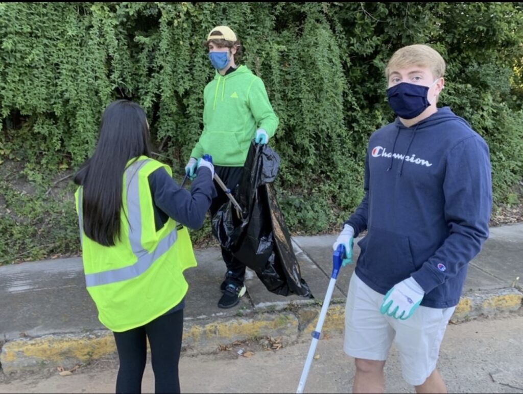 Three students pick up trash in the community.