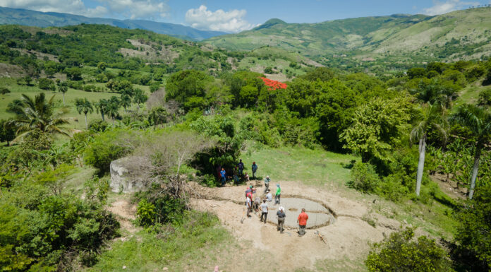 Mercerians make lasting impact in Dominican Republic through water access work A group of people dig a trench, with a view of the countryside in the background.