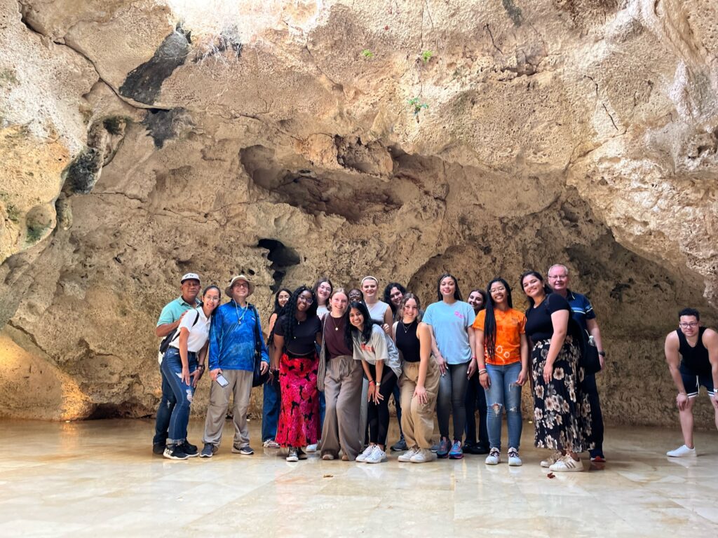 A group of students stands together in a cave.