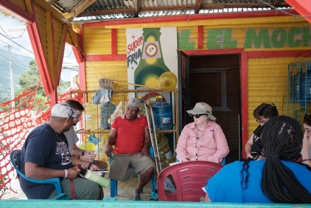 A group of people sit around a circle on a colorful porch.
