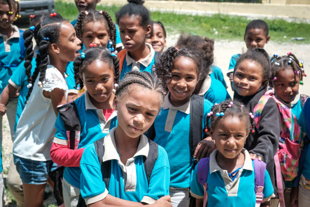 A group of children in blue uniform shirts are shown.