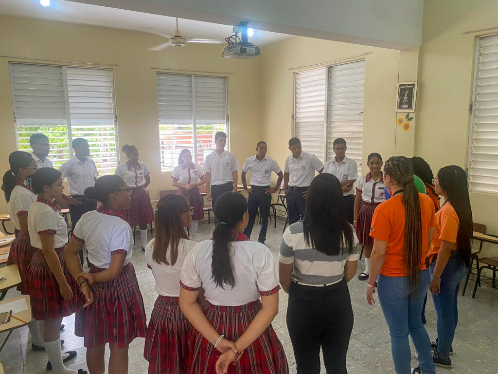 Dominican students in school uniforms stand in a circle with Mercer students.