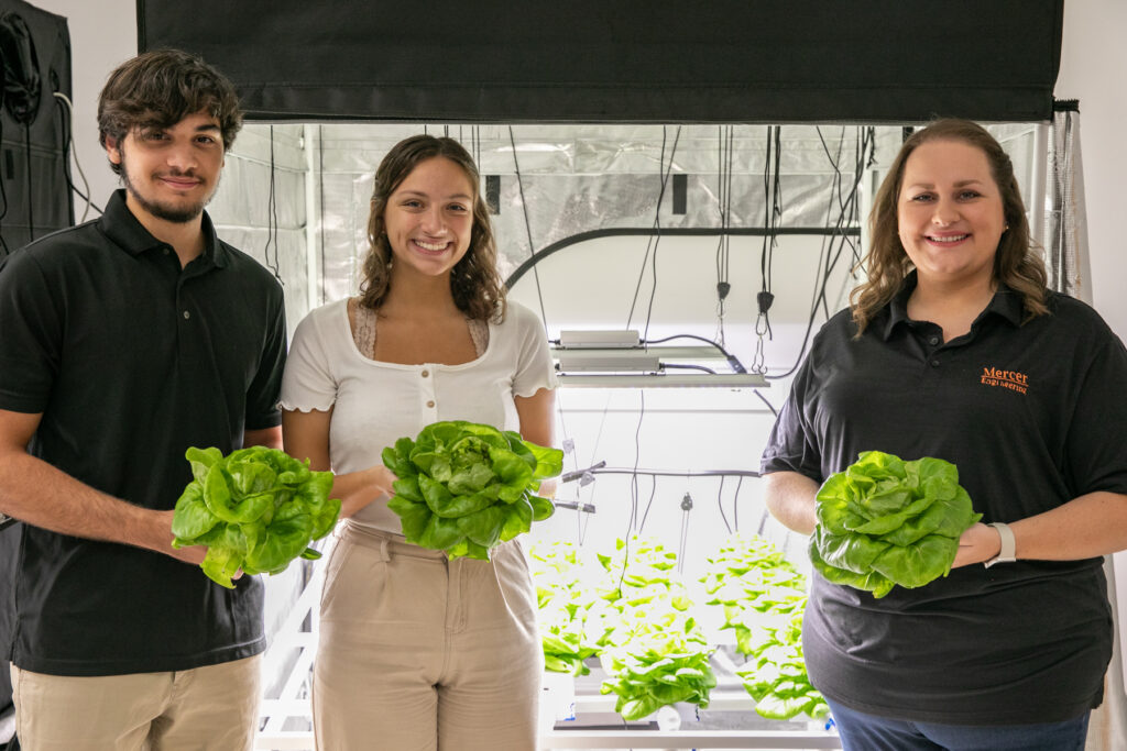 three people stand in a row holding lettuce