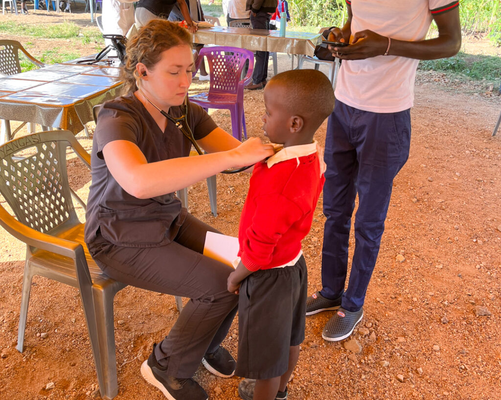 a female student uses a stethoscope to listen to a young boy's chest