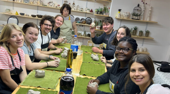 Students work with Ukrainian refugees during Mercer On Mission trip to Georgia Eight Mercer students sit at a table while working with clay.