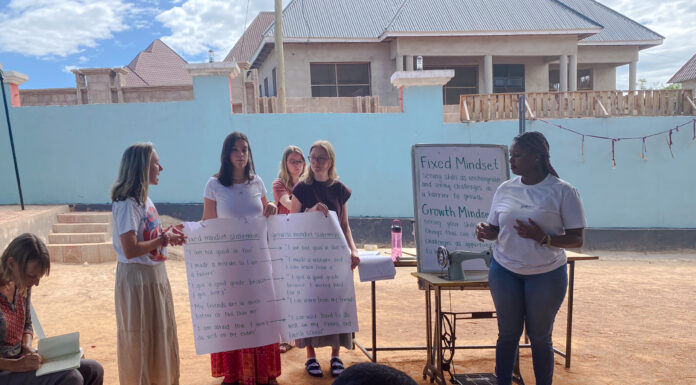 Mercer On Mission team works to reduce violence against women in Tanzania Students hold posters that explain fixed vs growth mindset
