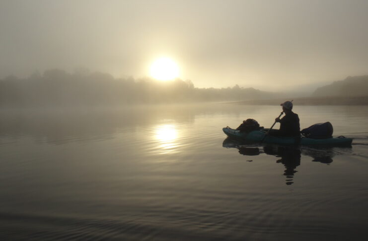 A man in a kayak are shown on a river.