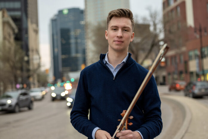 student standing in a city holds a violin