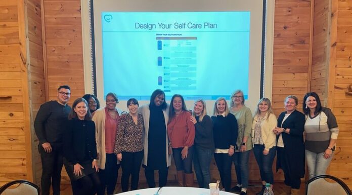 Counseling grads find new peace, passion through work with wellness firm A large group of people stands in front of a projector screen.
