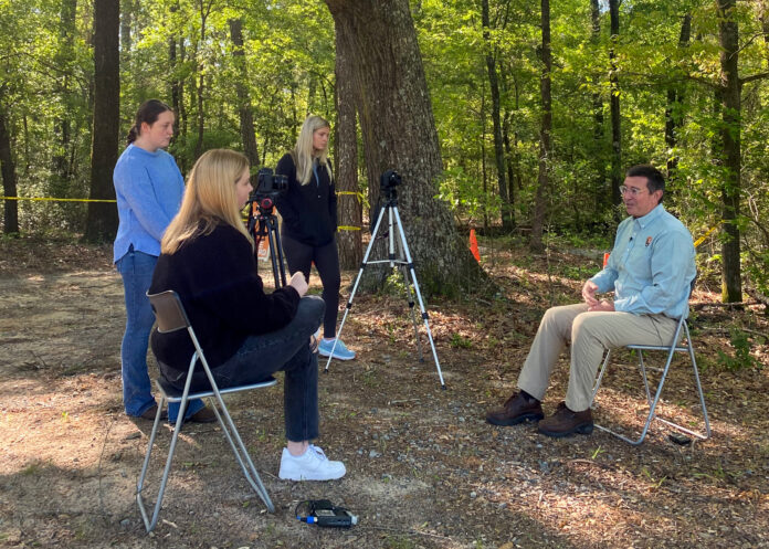 three students interview a man on camera
