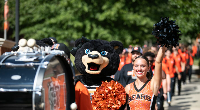 3 things to know about Mercer vs. VMI football game day: Sept. 30, 2023 a marching band member hits a bass drum, followed by a female bear mascot and cheerleader