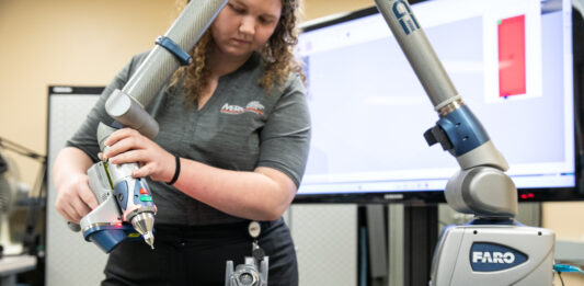 A woman points a laser at an aircraft part.