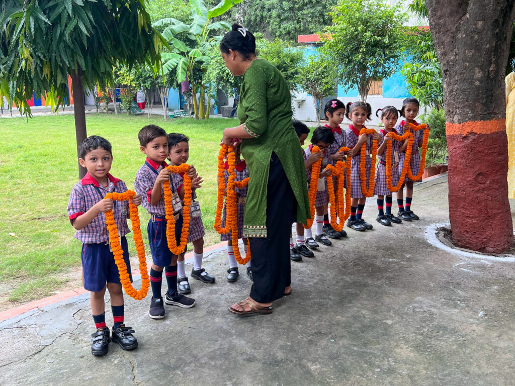 A teacher hands out flower leis to the children to present to the Mercer team.