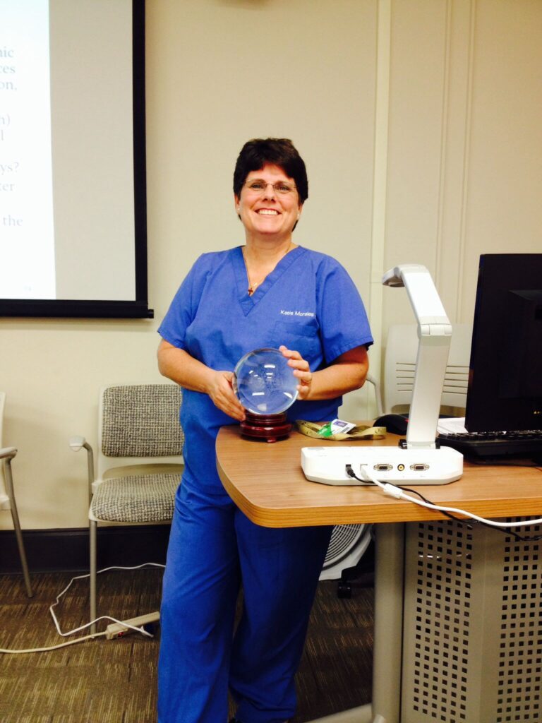 Dr. Katie Morales is shown in scrubs, holding a crystal ball.