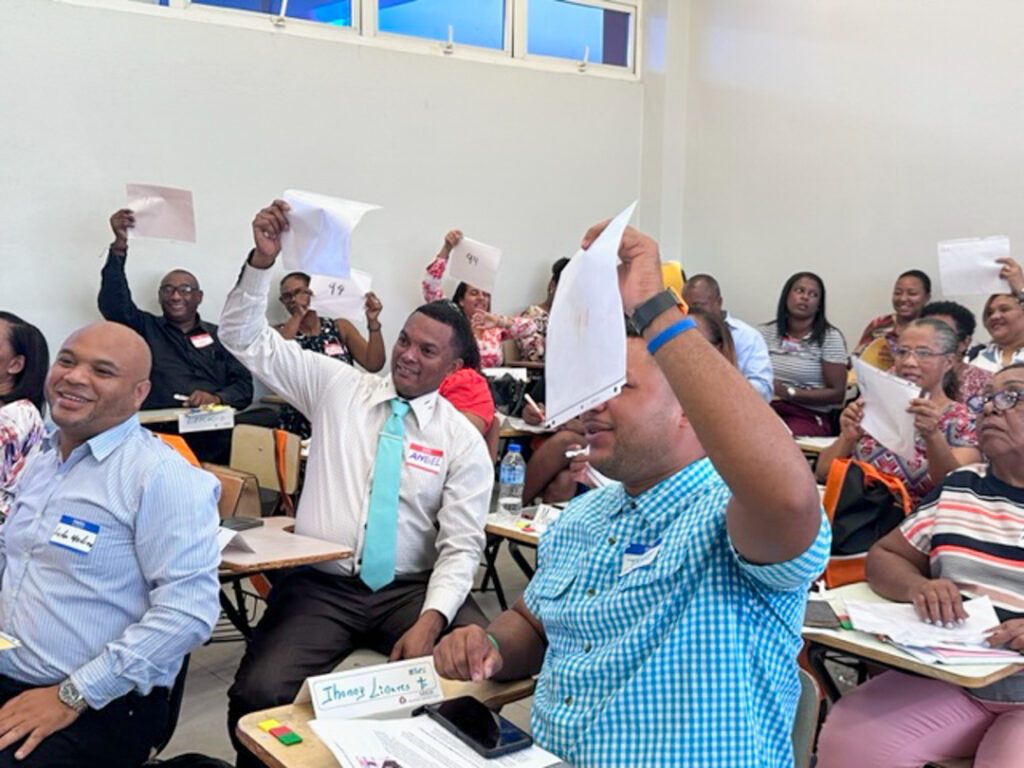 A classroom of adults holds up pieces of paper