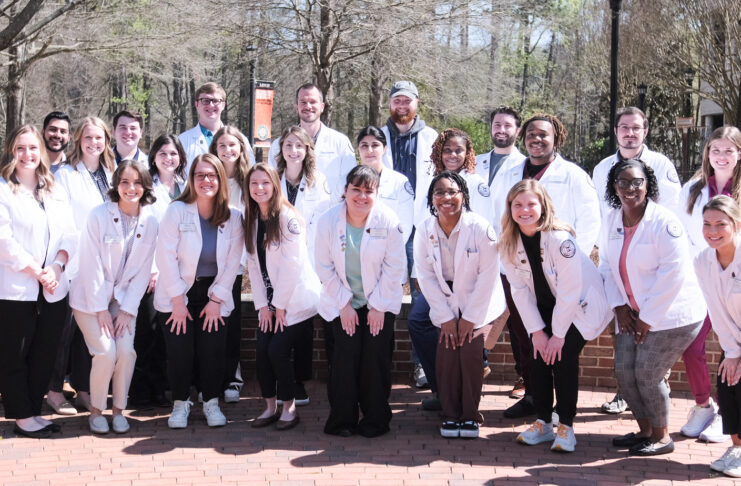 a group of people in white coats pose for a photo