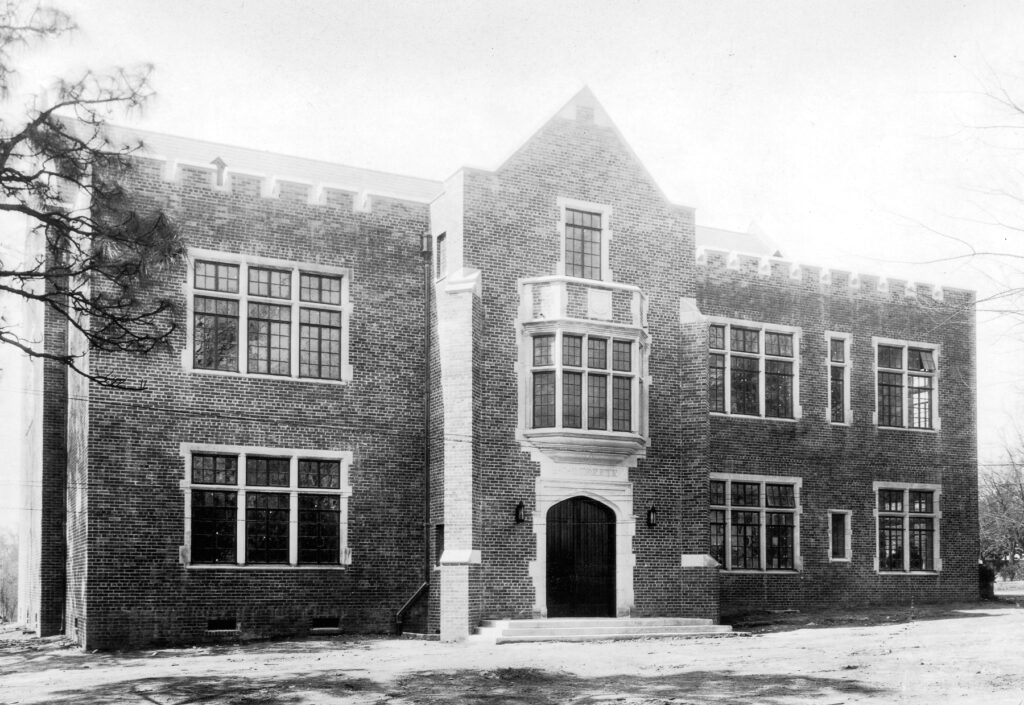 black and white photo of a brick building with a door and rectangle windows