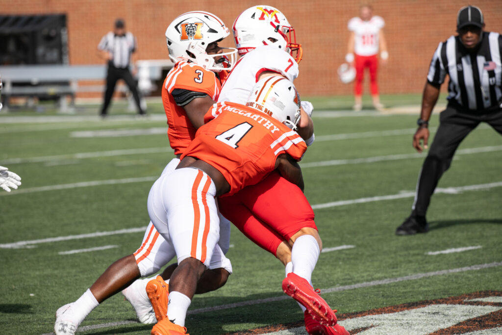 two mercer football players tackle a VMI football player