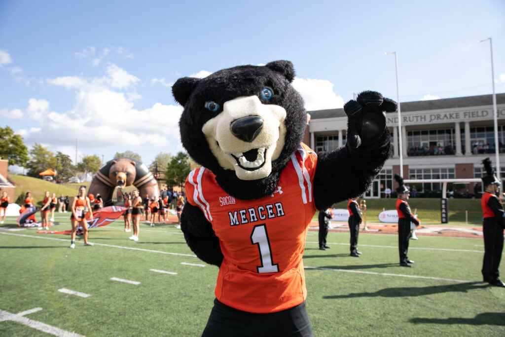 toby bear mascot gives the claw while standing on a football field
