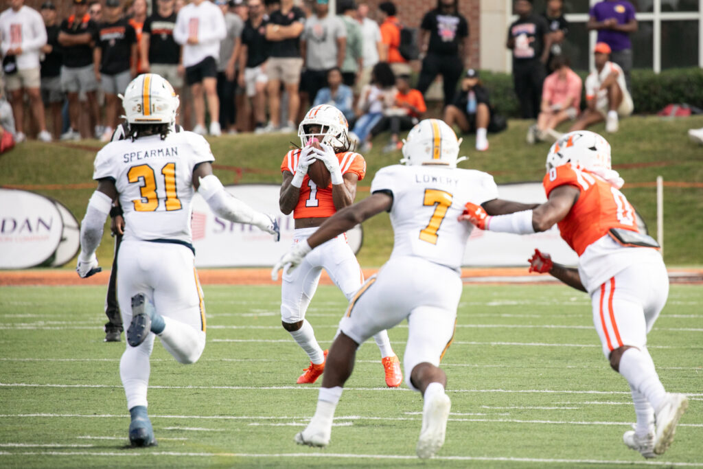 mercer football player catches ball as chattanooga football players run at him