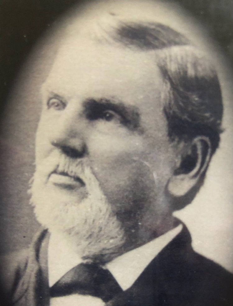 black and white headshot of a bearded man in a suit