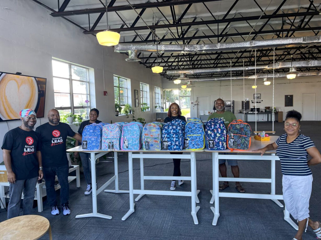 people stand behind colorful backpacks set on a table