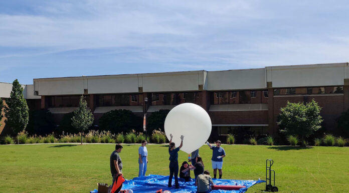 Engineering students to participate in NASA mission during annular solar eclipse students in a field blow up a big white balloon