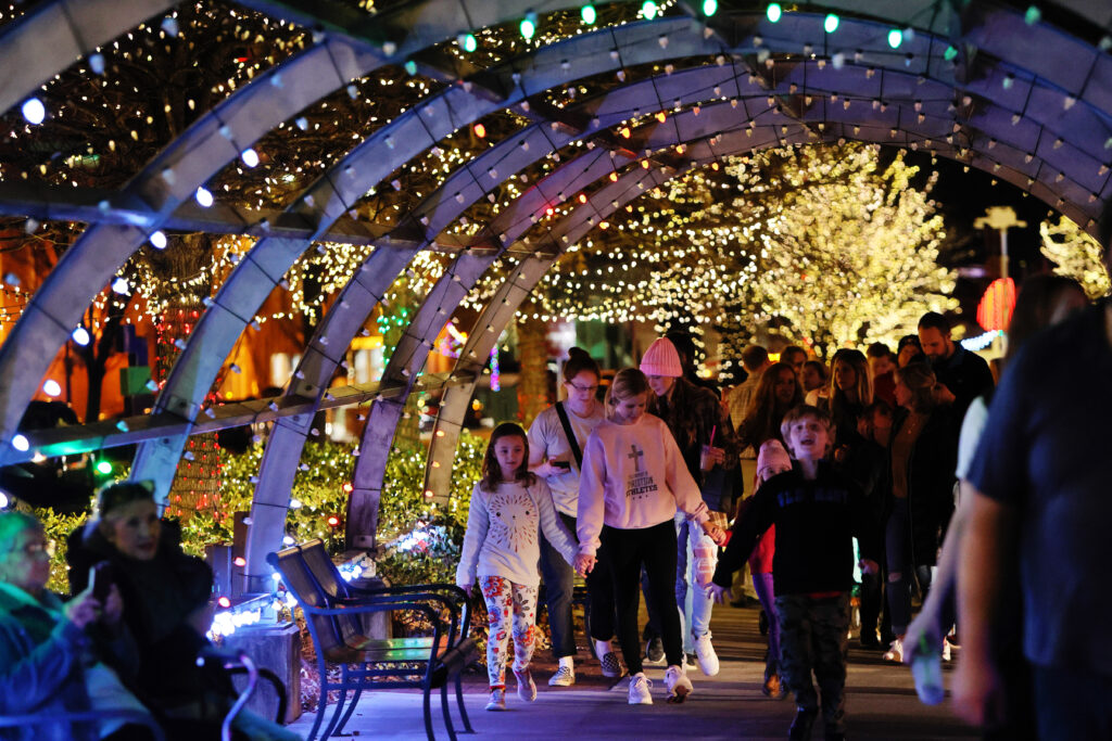 People walk under a canopy of lights.
