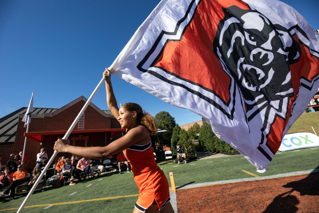 a cheerleader runs with a mercer flag