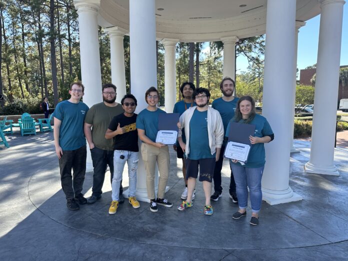 Eight smiling college students standing in front of columns holding award certificates