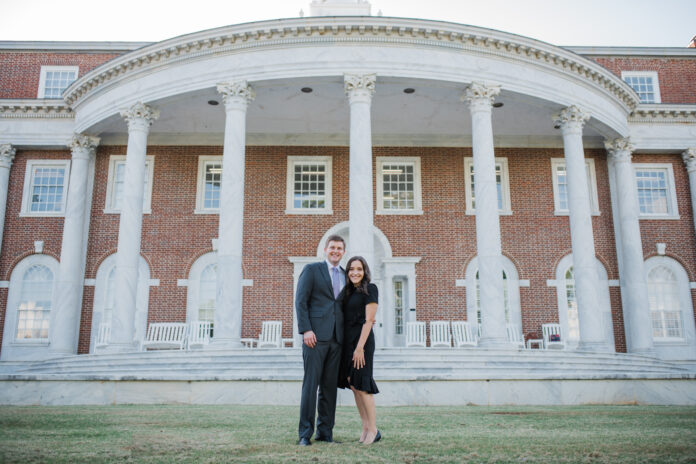 A couple stands in front of a large stately building with white columns and stairs.