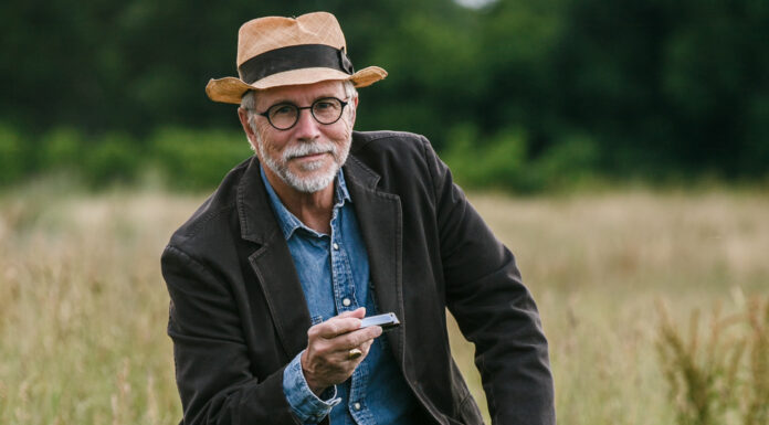 Alumnus’ 30-year recording career includes 20 albums and a popular Christmas song a man holds a harmonica