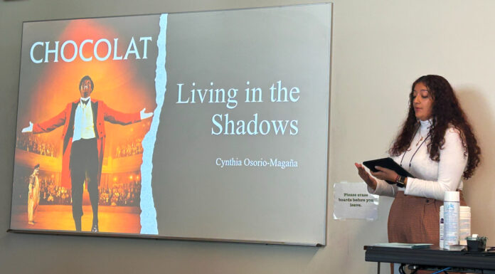 Students learn French history and culture through film | Classroom Spotlight The movie cover of chocolat is projected on a screen and a student stands to the right of the screen