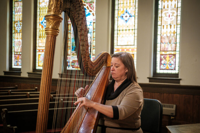 seated woman plays harp
