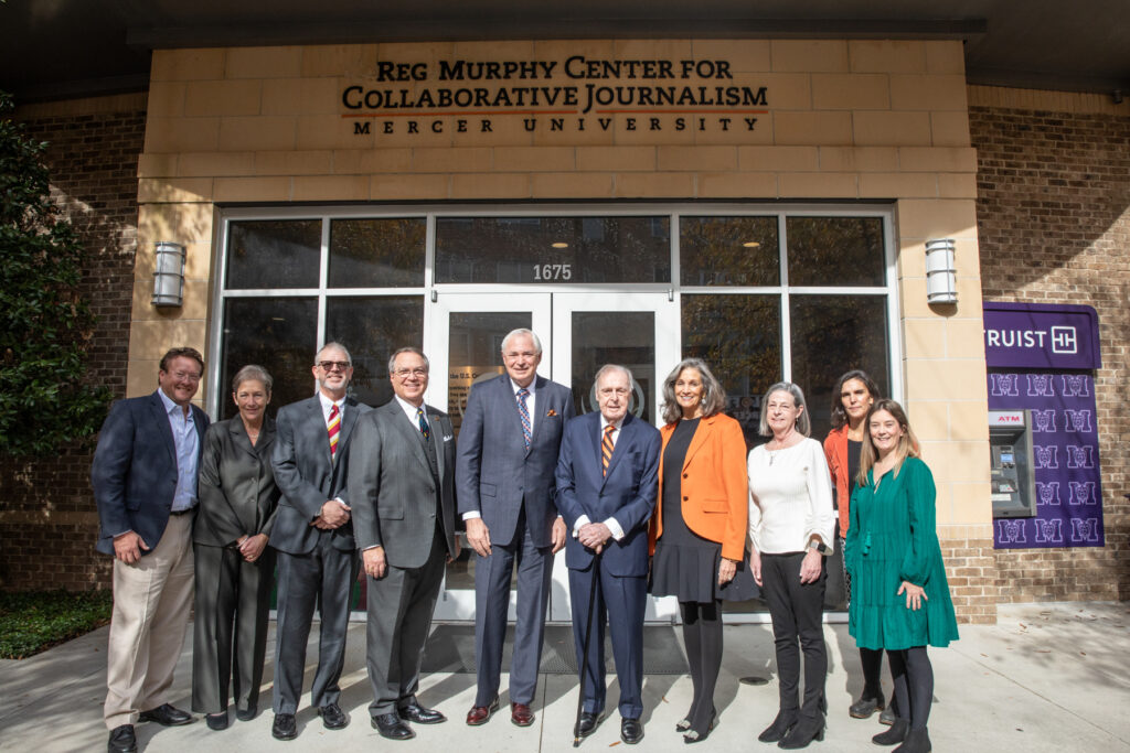 A group of people stand in front of a building that bears the name Reg Murphy Center for Collaborative Journalism