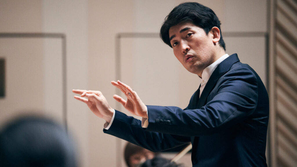 A man uses his hands to conduct an orchestra.