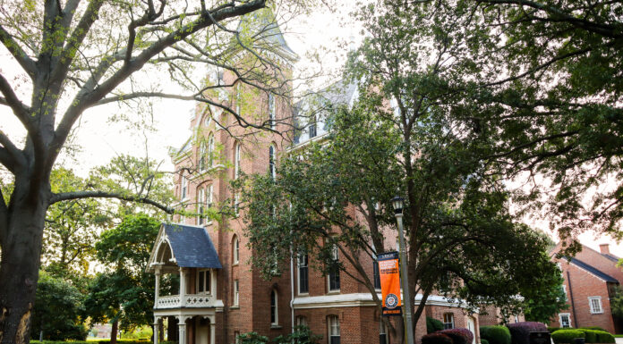 Renowned Chicago architect built Mercer’s Godsey Administration Building 150 years ago A tall brick building is highlighted by the sun and surrounded by trees.