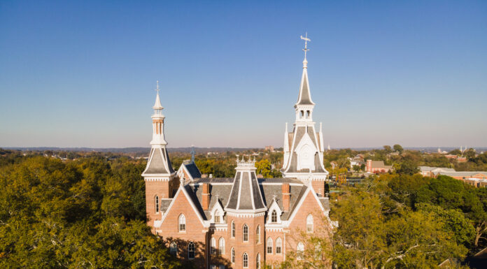 Board of trustees executive committee appoints Presidential Search Committee A drone photo of a five-story brick building with tall spires, with trees surrounding it.
